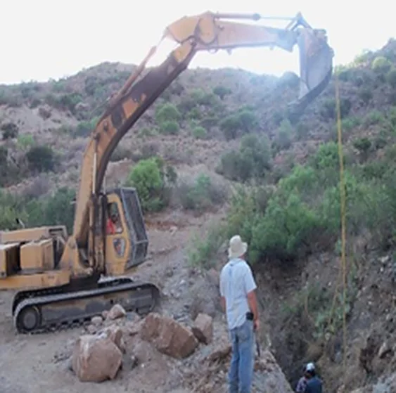 Excavadora y personal en la apertura de un tiro sobre la ladera