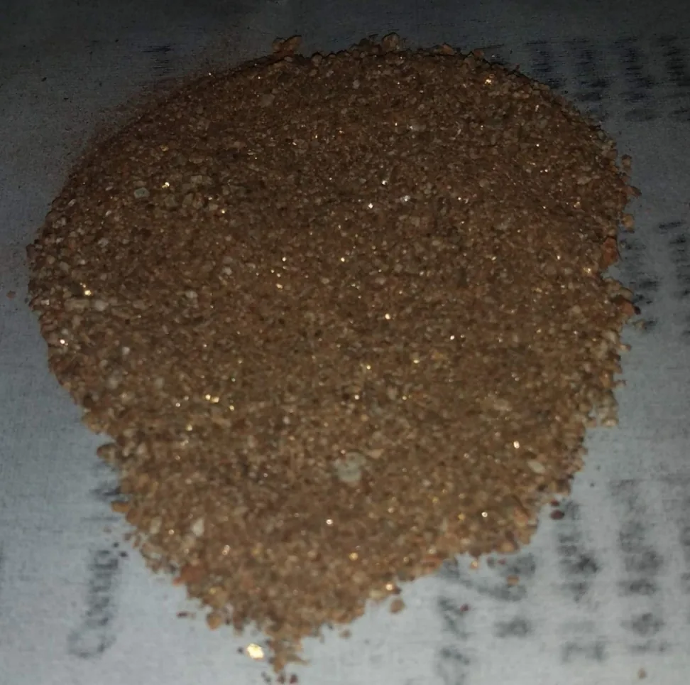 Muestra de concentrado mineral en polvo con partículas metálicas brillantes