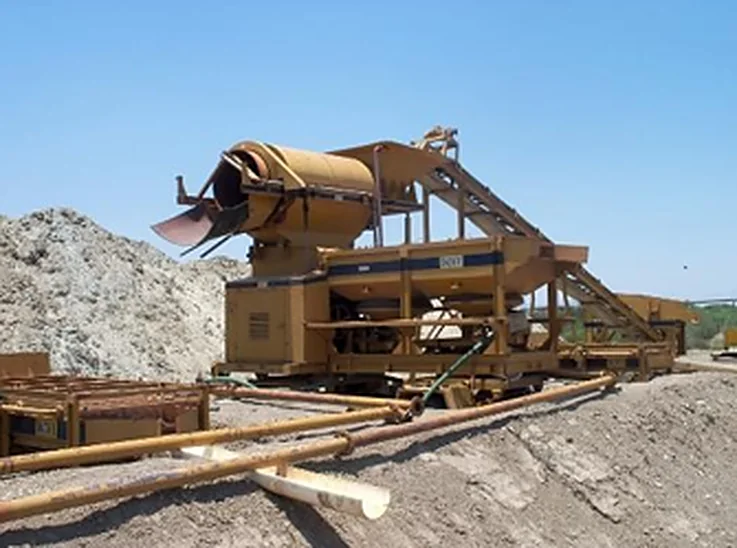 Trommel de lavado y clasificación junto a una pila de material